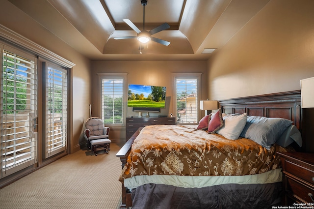 bedroom featuring ceiling fan, a raised ceiling, and light carpet