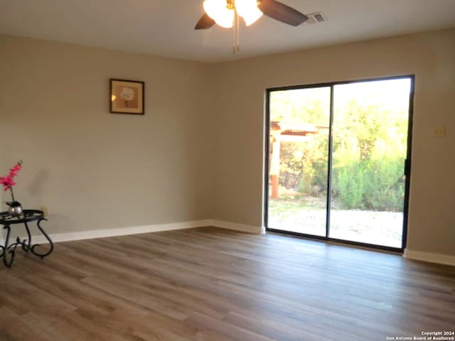 spare room with a healthy amount of sunlight, dark wood-type flooring, and ceiling fan