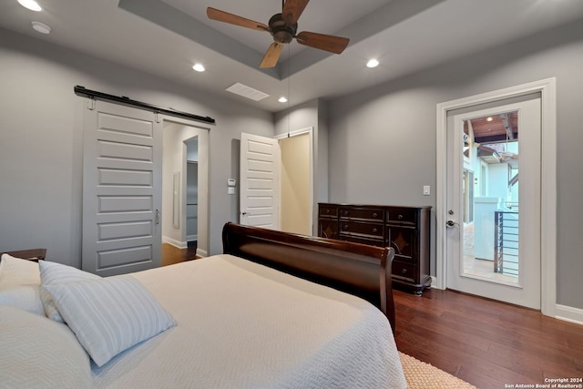 bedroom featuring a barn door, dark hardwood / wood-style floors, access to outside, and ceiling fan