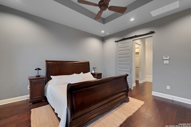 bedroom featuring a barn door, dark wood-type flooring, and ceiling fan