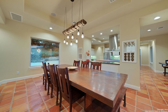 dining area with light tile floors and a raised ceiling