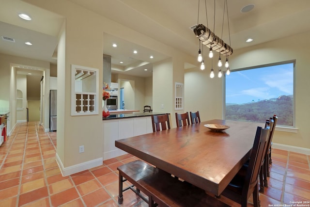 dining room featuring a mountain view, a tray ceiling, and light tile flooring