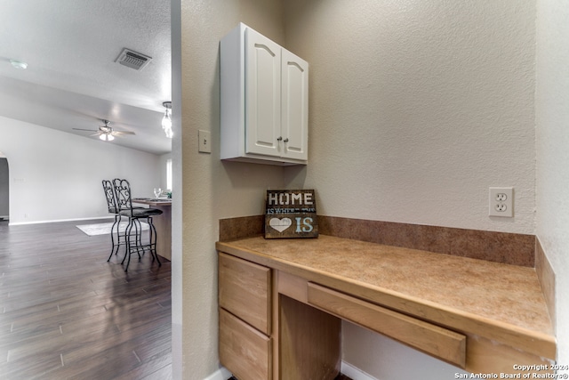 kitchen featuring dark wood-type flooring, white cabinets, ceiling fan, and a textured ceiling