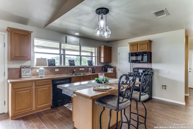 kitchen with dark wood-type flooring, a kitchen island, black appliances, tile countertops, and sink