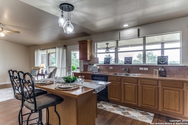 kitchen featuring ceiling fan, hardwood / wood-style floors, black dishwasher, backsplash, and sink