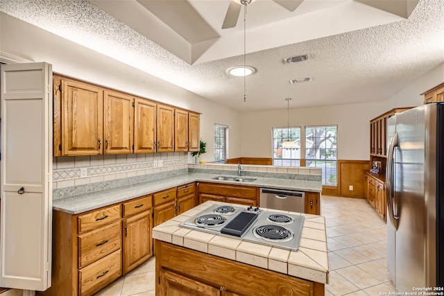 kitchen with appliances with stainless steel finishes, kitchen peninsula, sink, and a kitchen island