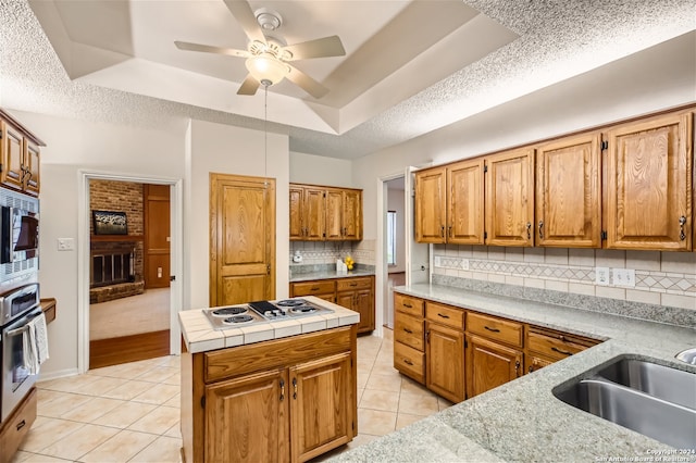 kitchen featuring stainless steel appliances, a kitchen island, light tile patterned flooring, and a tray ceiling