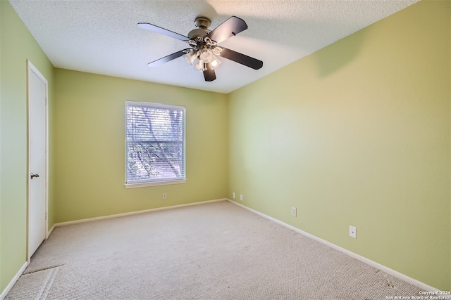 unfurnished room with a textured ceiling, ceiling fan, and light carpet