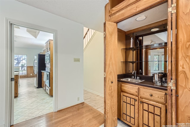 bar with sink, light hardwood / wood-style flooring, and appliances with stainless steel finishes