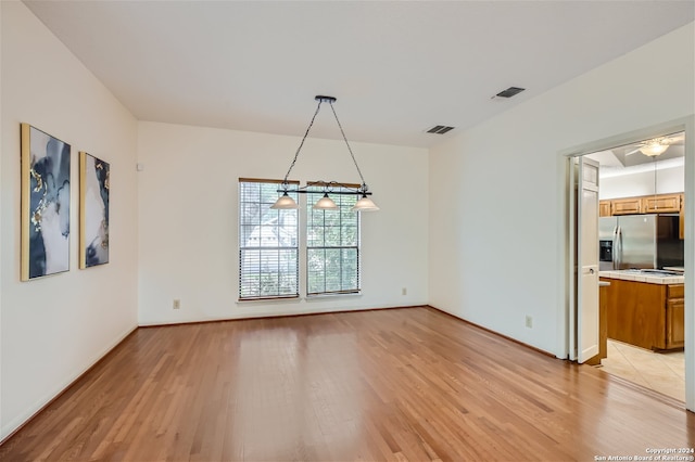 unfurnished dining area with light wood-type flooring and ceiling fan