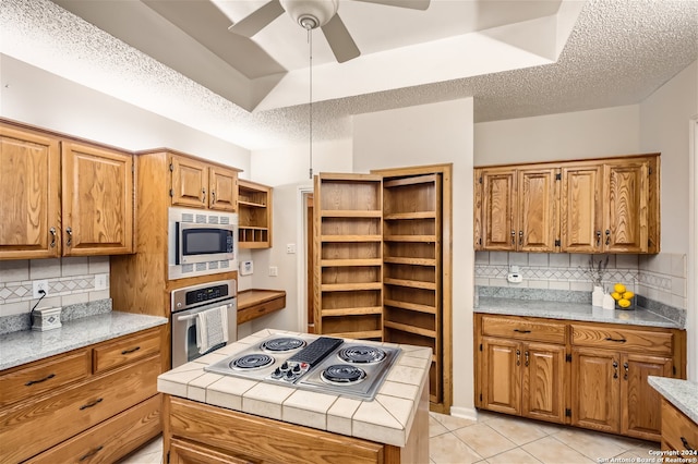 kitchen featuring stainless steel appliances, a textured ceiling, light tile patterned flooring, ceiling fan, and tasteful backsplash