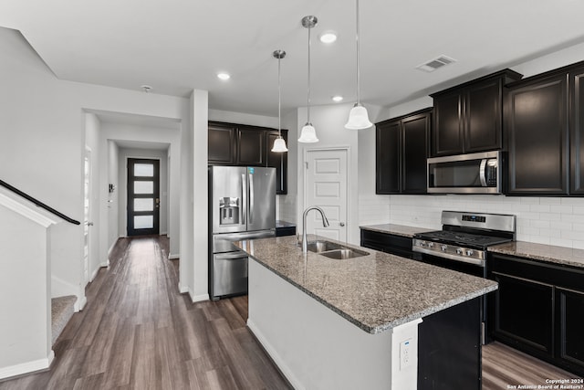 kitchen featuring a center island with sink, appliances with stainless steel finishes, hardwood / wood-style floors, sink, and tasteful backsplash