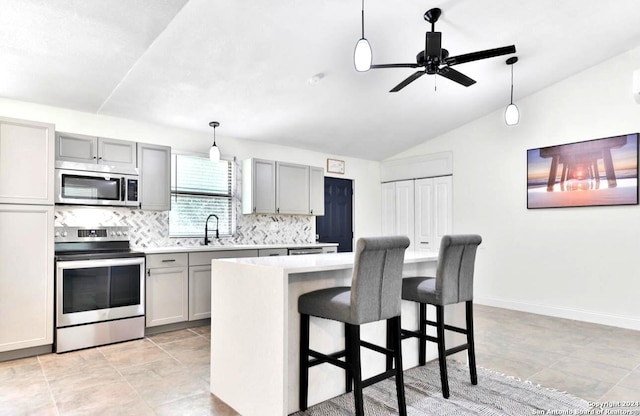 kitchen featuring stainless steel appliances, gray cabinetry, light tile floors, and lofted ceiling