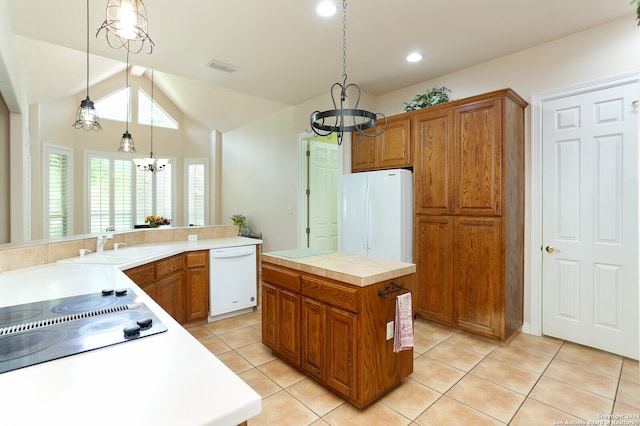 kitchen with a notable chandelier, a kitchen island, sink, white appliances, and hanging light fixtures