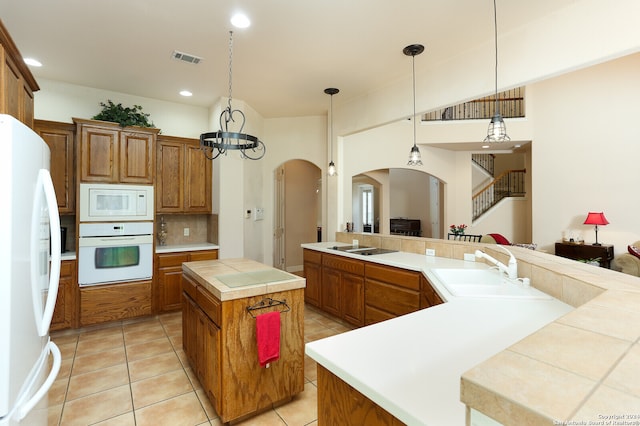 kitchen featuring backsplash, white appliances, a kitchen island, pendant lighting, and sink