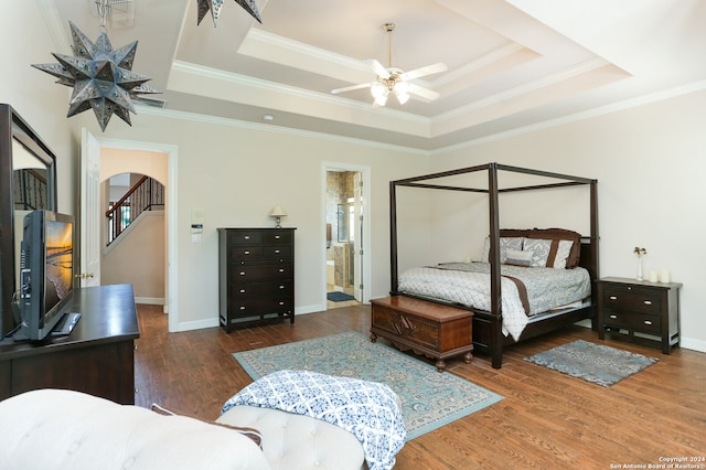 bedroom with ceiling fan, dark hardwood / wood-style flooring, a raised ceiling, and ensuite bath