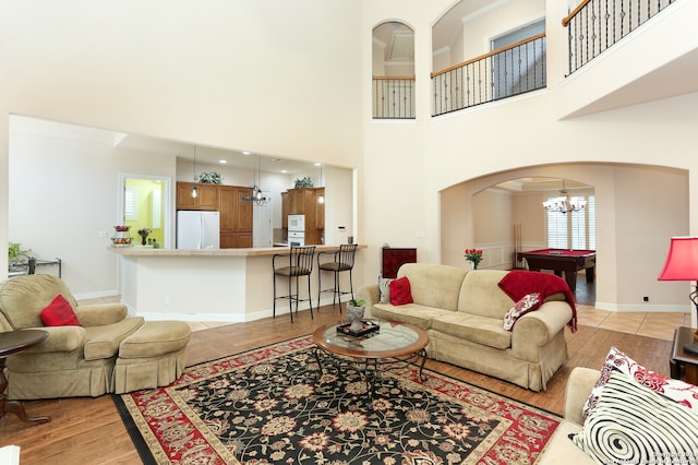 living room featuring a chandelier, light hardwood / wood-style floors, pool table, and a high ceiling