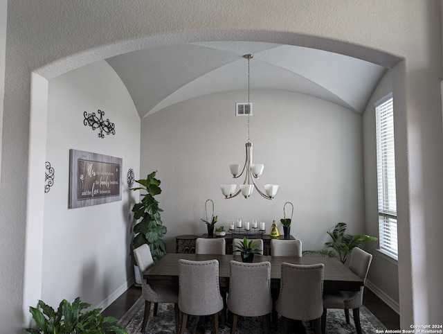 dining space featuring a healthy amount of sunlight, vaulted ceiling, a notable chandelier, and wood-type flooring