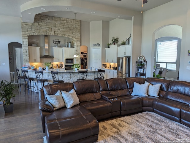 living room with ceiling fan, dark hardwood / wood-style flooring, and a towering ceiling