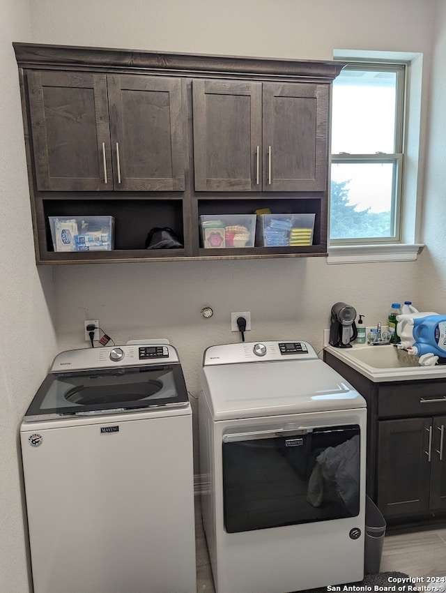 laundry area featuring sink, independent washer and dryer, and cabinets