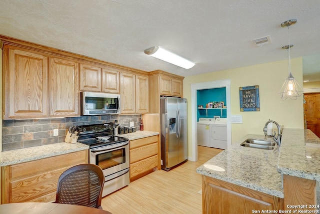 kitchen featuring independent washer and dryer, light hardwood / wood-style flooring, stainless steel appliances, backsplash, and sink