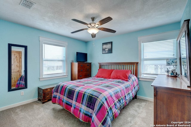 bedroom featuring light colored carpet, ceiling fan, and multiple windows