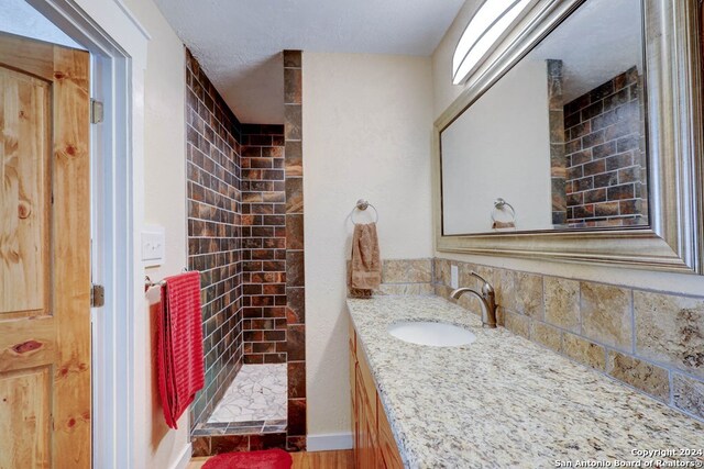 bathroom with walk in shower, a textured ceiling, and oversized vanity