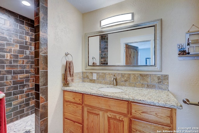 bathroom with a textured ceiling, tasteful backsplash, and vanity