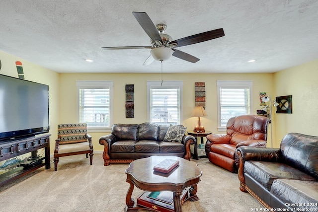 living room featuring light carpet, a healthy amount of sunlight, a textured ceiling, and ceiling fan