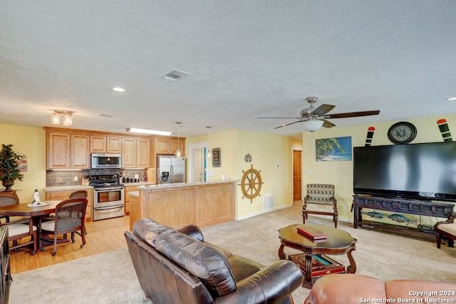 living room with ceiling fan, a textured ceiling, and light wood-type flooring