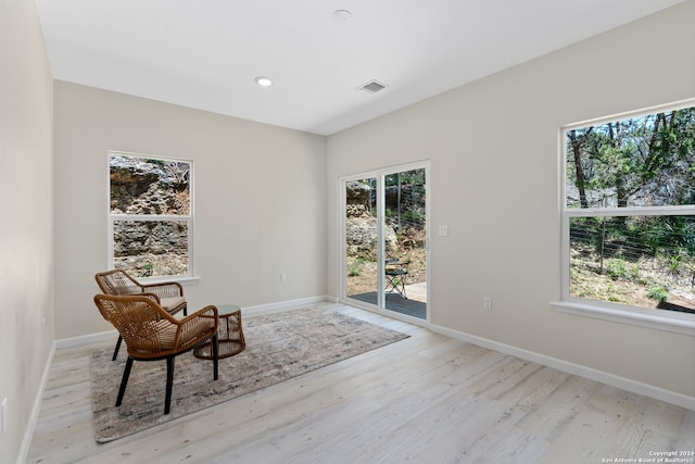 living area with a wealth of natural light and light hardwood / wood-style flooring