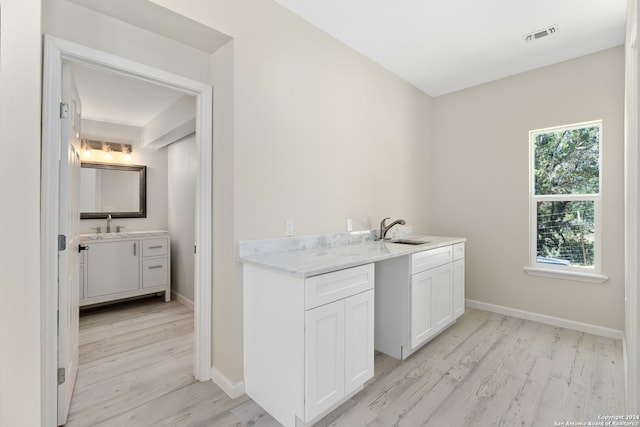 bar featuring light hardwood / wood-style floors, white cabinets, sink, and plenty of natural light