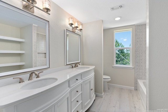 full bathroom featuring vanity with extensive cabinet space, dual sinks, toilet, wood-type flooring, and bathing tub / shower combination