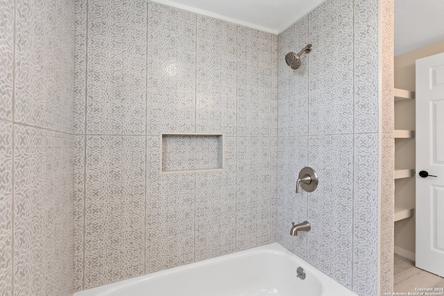 bathroom featuring built in shelves and tiled shower / bath combo