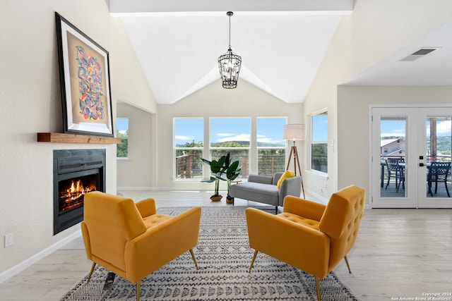 living room featuring plenty of natural light, light hardwood / wood-style floors, french doors, and high vaulted ceiling