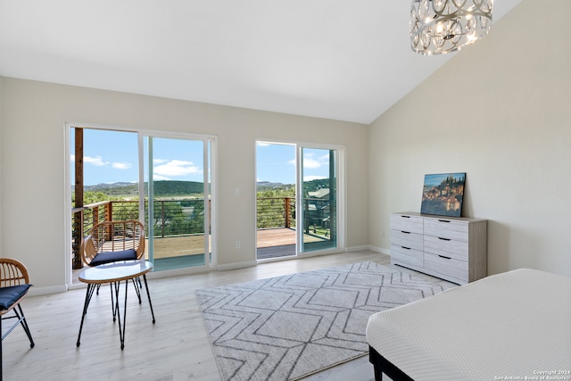 bedroom featuring high vaulted ceiling, an inviting chandelier, light wood-type flooring, and access to outside