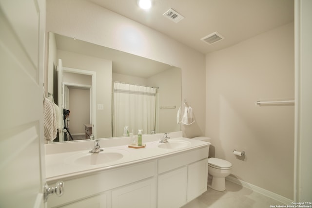 bathroom with tile floors, large vanity, toilet, and double sink