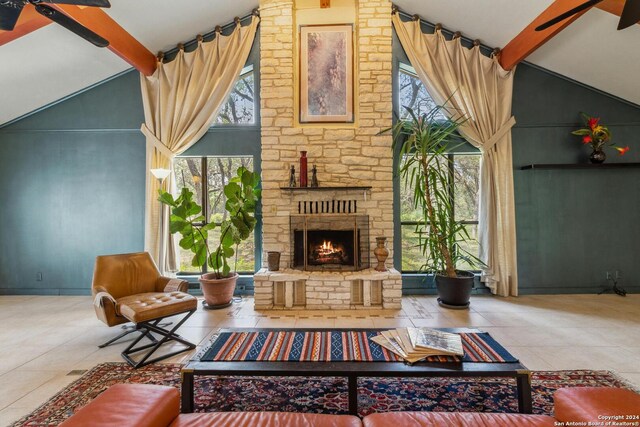 tiled living room with ceiling fan, beam ceiling, a fireplace, and high vaulted ceiling