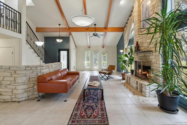 tiled living room with a stone fireplace, high vaulted ceiling, ceiling fan, and beamed ceiling