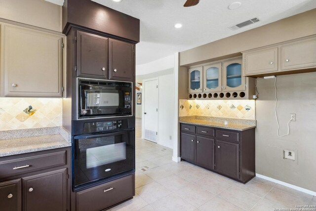 kitchen with light stone counters, backsplash, black appliances, dark brown cabinets, and light tile floors