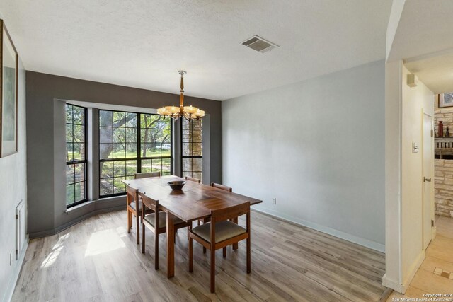 dining area featuring a wealth of natural light, a chandelier, light hardwood / wood-style flooring, and a textured ceiling