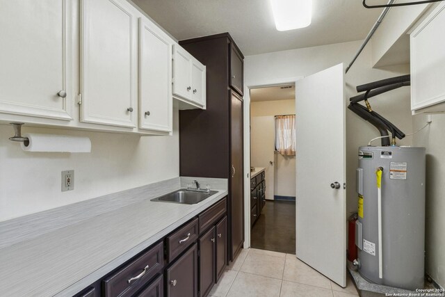 kitchen featuring white cabinetry, dark brown cabinets, water heater, sink, and light tile flooring