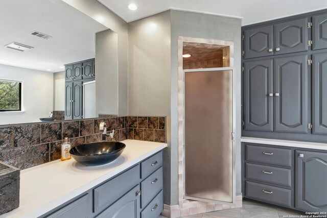 bathroom with walk in shower, tile flooring, vanity with extensive cabinet space, and tasteful backsplash