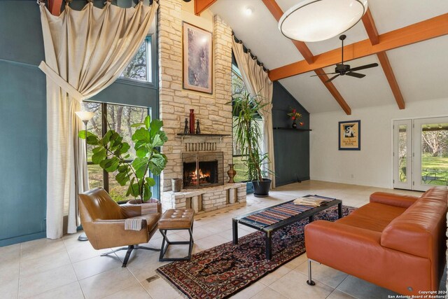 tiled living room with plenty of natural light, beam ceiling, and a stone fireplace