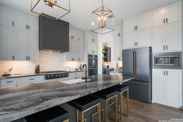 kitchen featuring pendant lighting, backsplash, wall chimney range hood, a breakfast bar, and appliances with stainless steel finishes