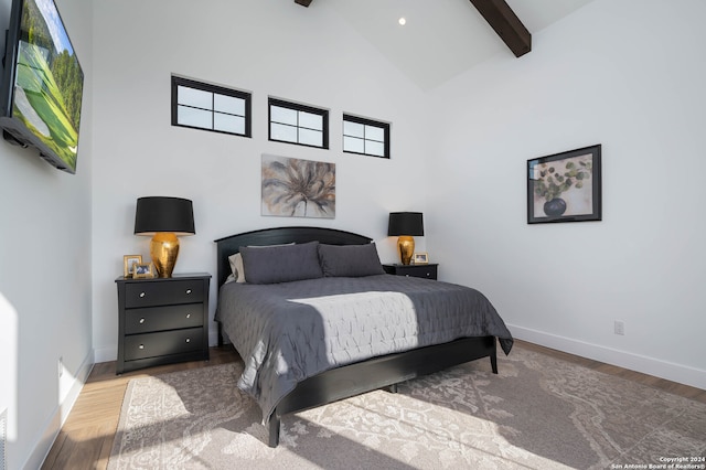 bedroom featuring high vaulted ceiling, hardwood / wood-style flooring, beam ceiling, and multiple windows