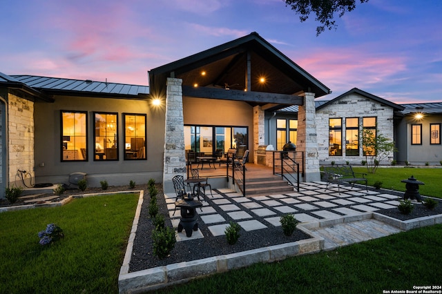back house at dusk with a patio area and a yard
