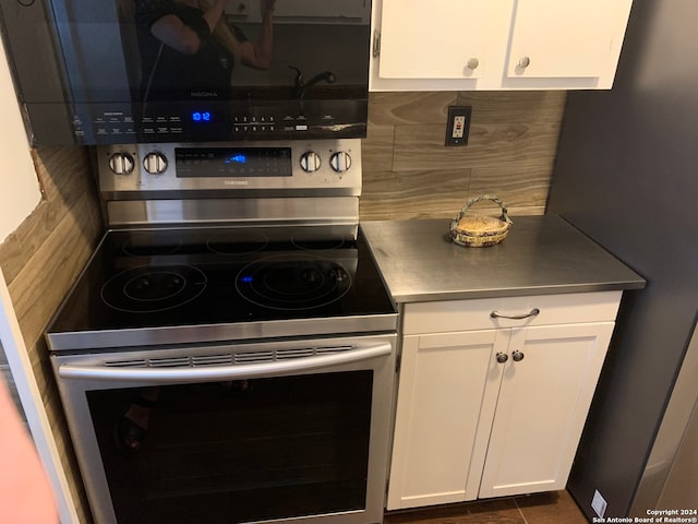 kitchen with backsplash, white cabinets, and stainless steel electric stove