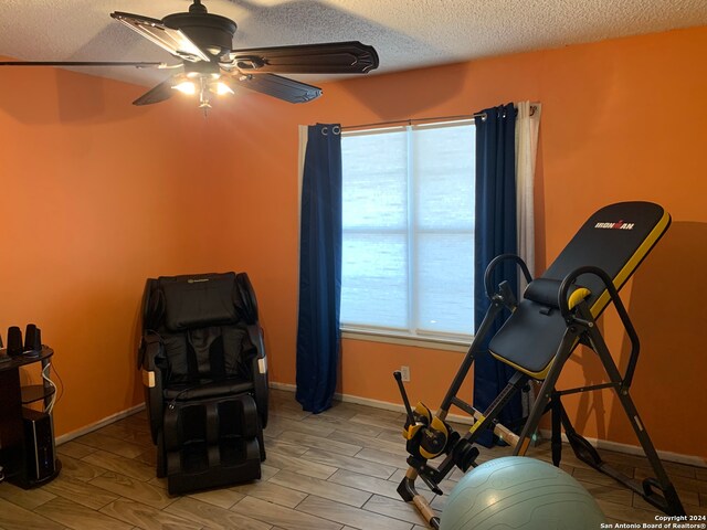 workout room with wood-type flooring, ceiling fan, and a textured ceiling