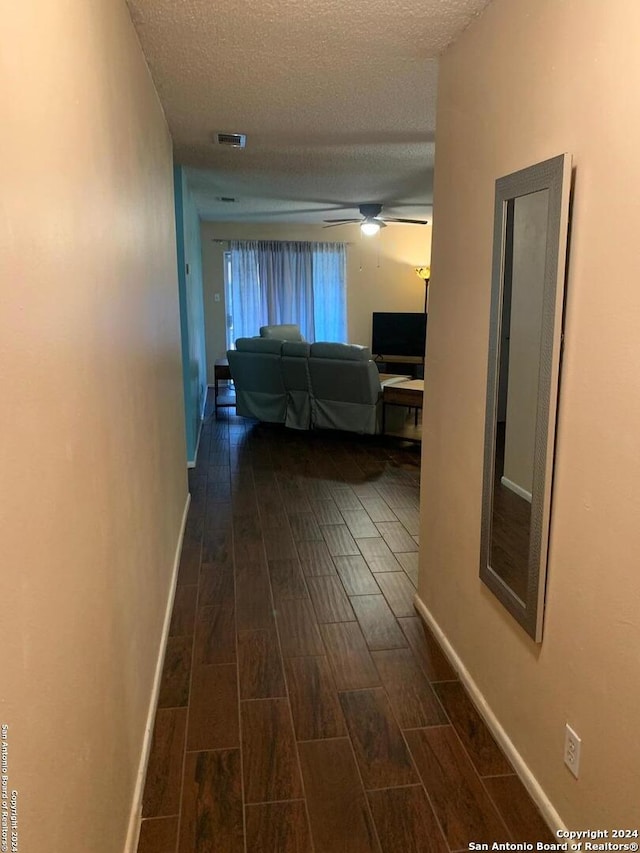 corridor with dark hardwood / wood-style floors and a textured ceiling